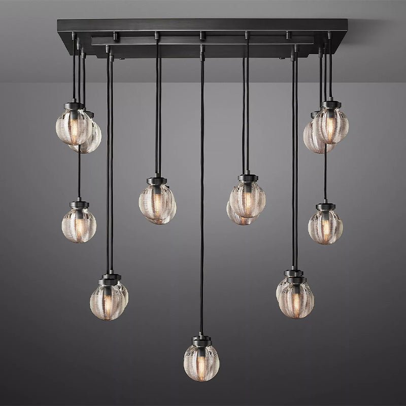 Black metal linear chandelier with nine ribbed glass globe pendants hanging at varying heights against a gray background.