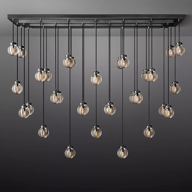 Multi-pendant chandelier with brushed metal frame and clear ribbed glass globes hanging at varying heights against a gray background.